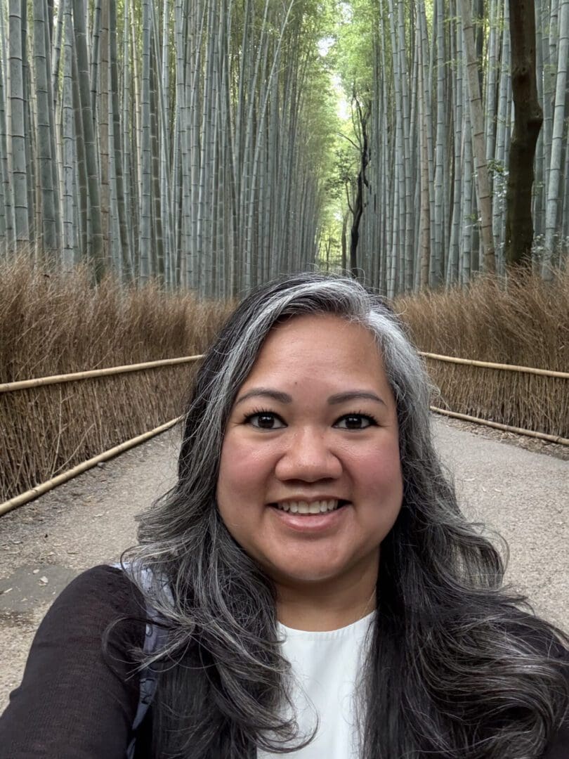 Woman smiling on a bamboo forest path.