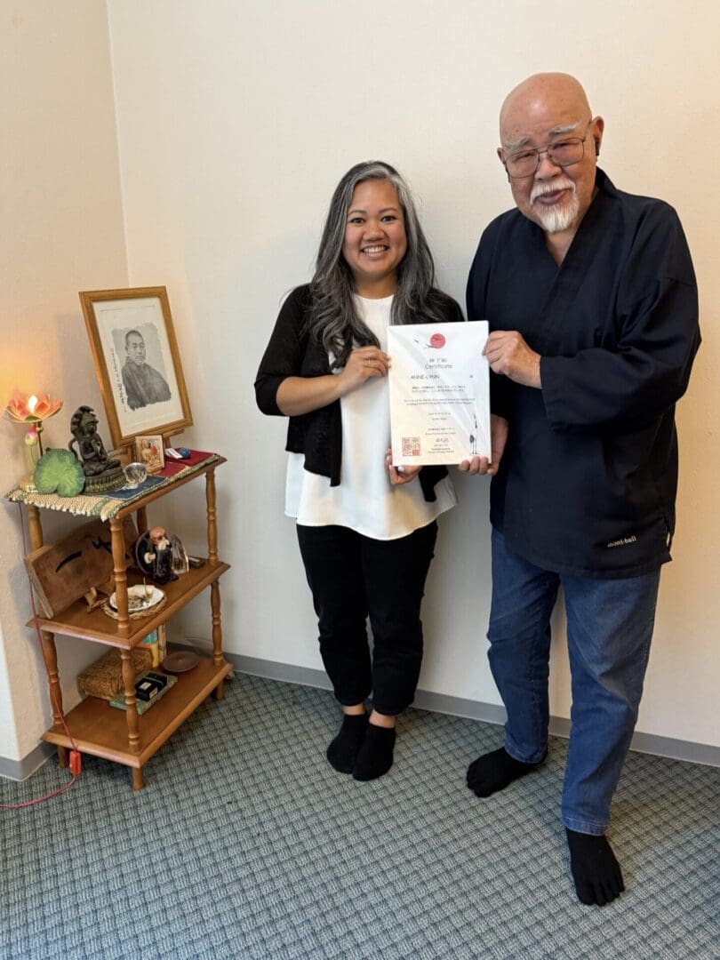 Two people smiling, holding a certificate indoors.