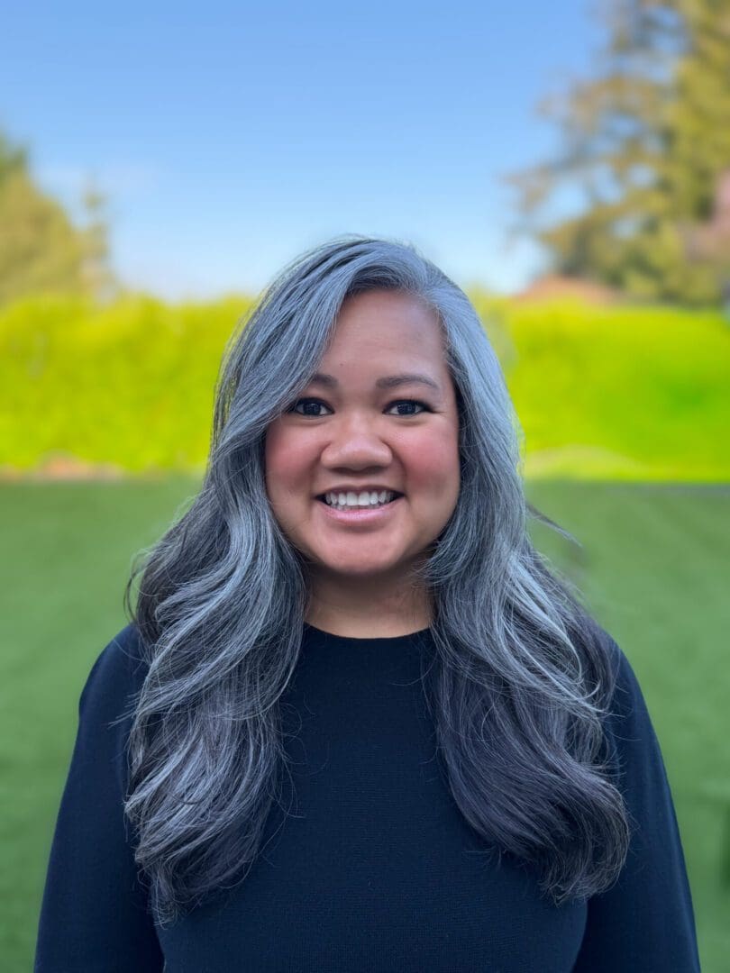 Smiling woman with long gray hair outdoors